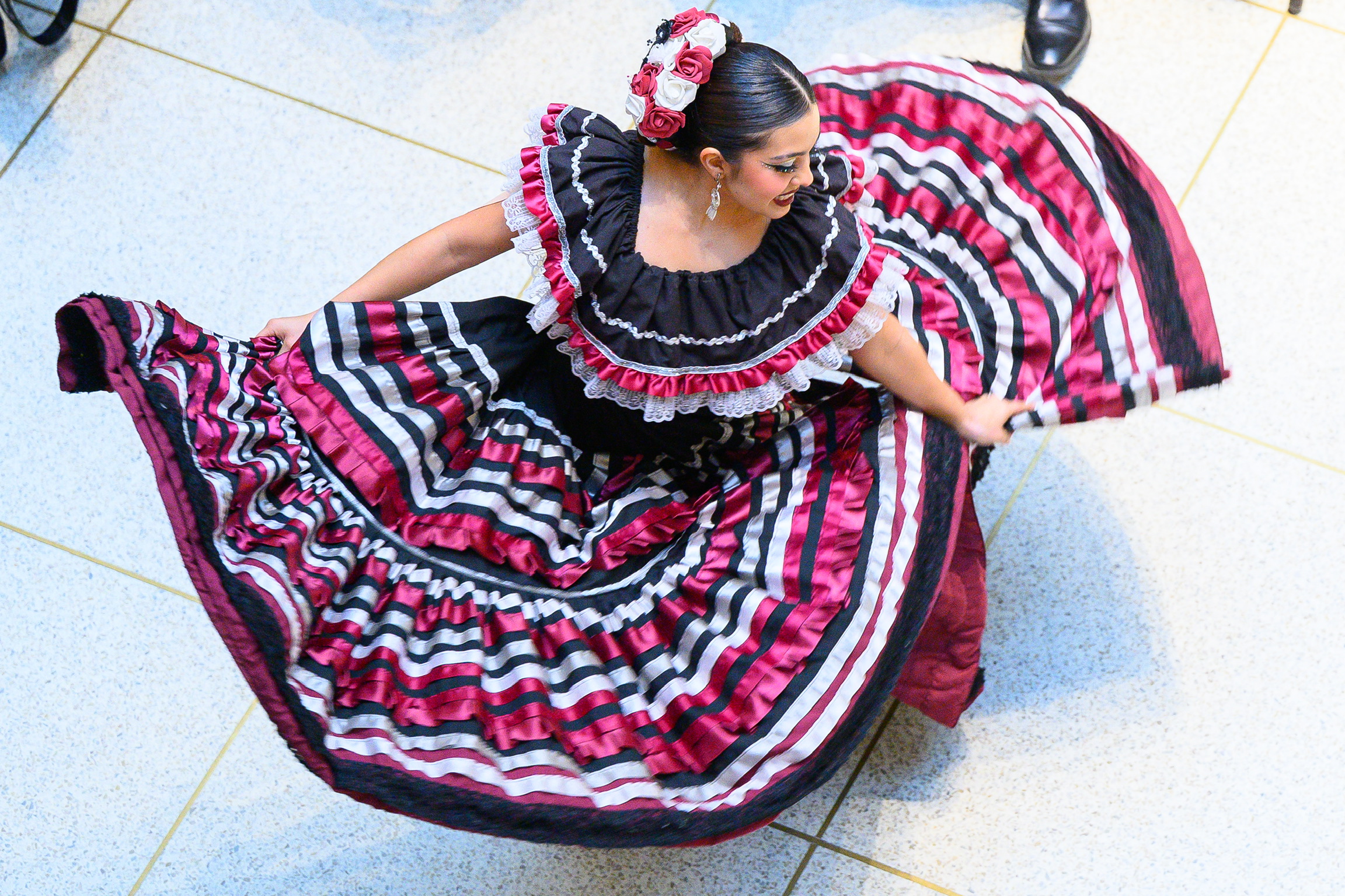 A dancer in a colorful traditional dress performs a folk dance, showcasing her vibrant attire and graceful movements.
